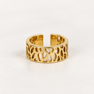 Anillo dorado calado sobre fondo crema